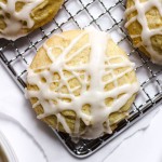 A lemon sugar cookie with lemon glaze on a wire cooling rack.