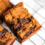 A slice of pumpkin chocolate chip banana bread on a wire cooling rack.