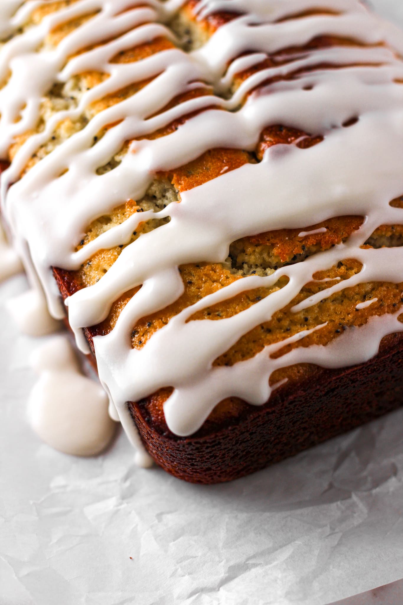 close up of a lemon glazed loaf on parchment paper for baked abundance blog