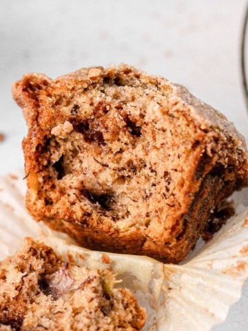 A cinnamon swirl banana muffin sitting on a muffin liner.