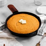 Sweet potato cornbread in a cast iron skillet with butter.