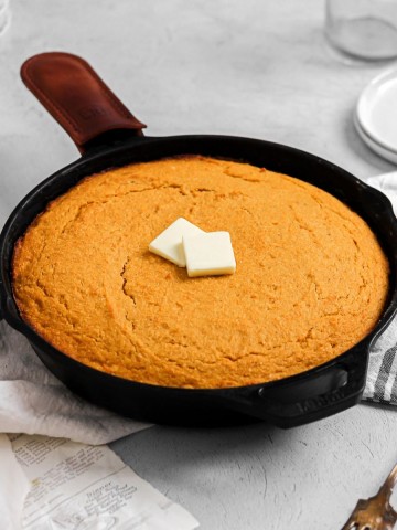 Sweet potato cornbread in a cast iron skillet with butter.
