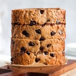 Slices of chocolate chip banana bread stacked on a wooden cutting board.