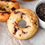 A cherry almond chocolate chip baked donut on parchment paper.
