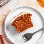 Half of a pumpkin cream cheese cupcake on a small plate with a fork.