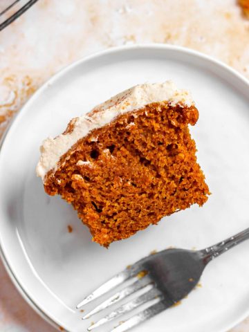 Half of a pumpkin cream cheese cupcake on a small plate with a fork.