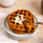 A stack of mini pumpkin waffles with butter.
