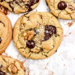 Chocolate chip walnut cookies on a parchment lined baking sheet.