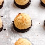 Coconut macaroons dipped in chocolate on parchment paper.