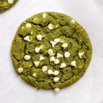 Matcha cookies with white chocolate chips on parchment paper.