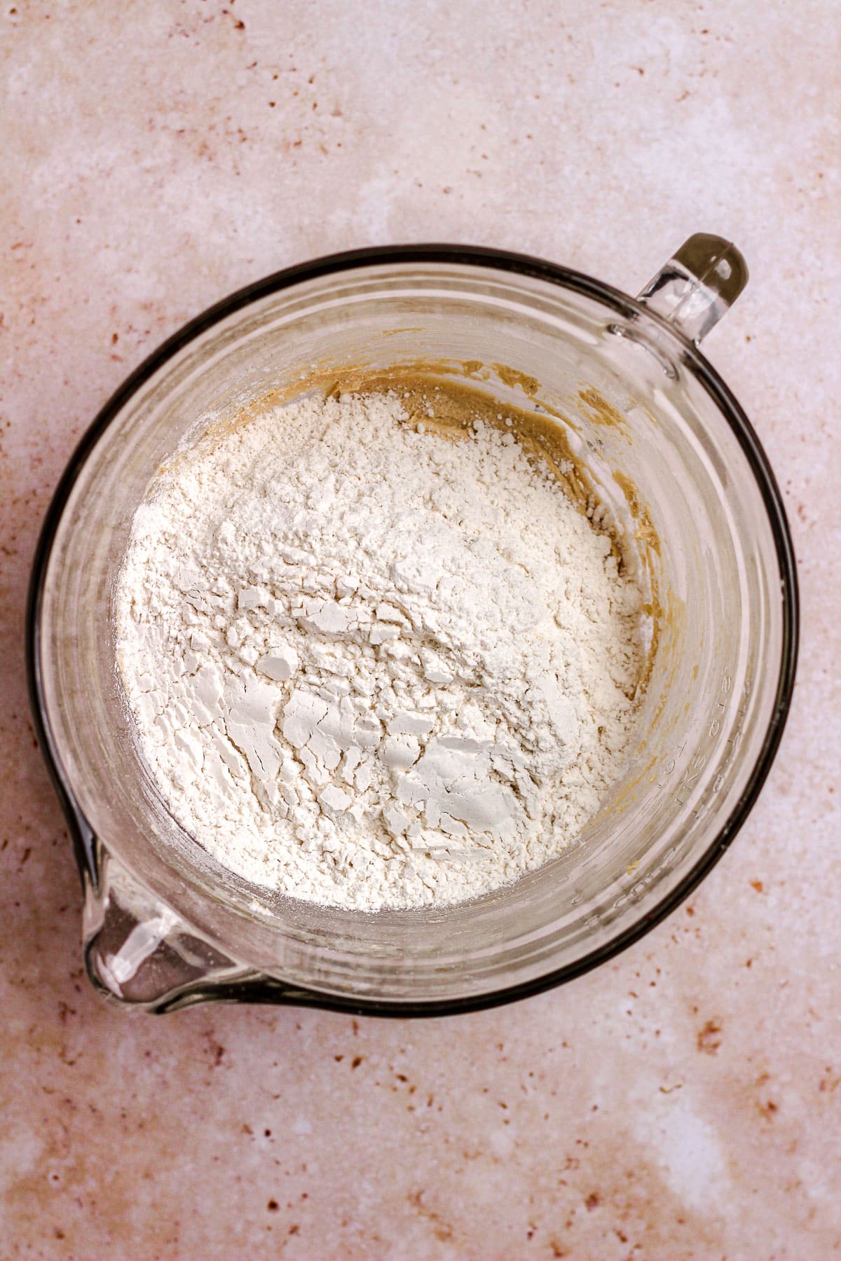 A glass bowl with cookie dough and flour.
