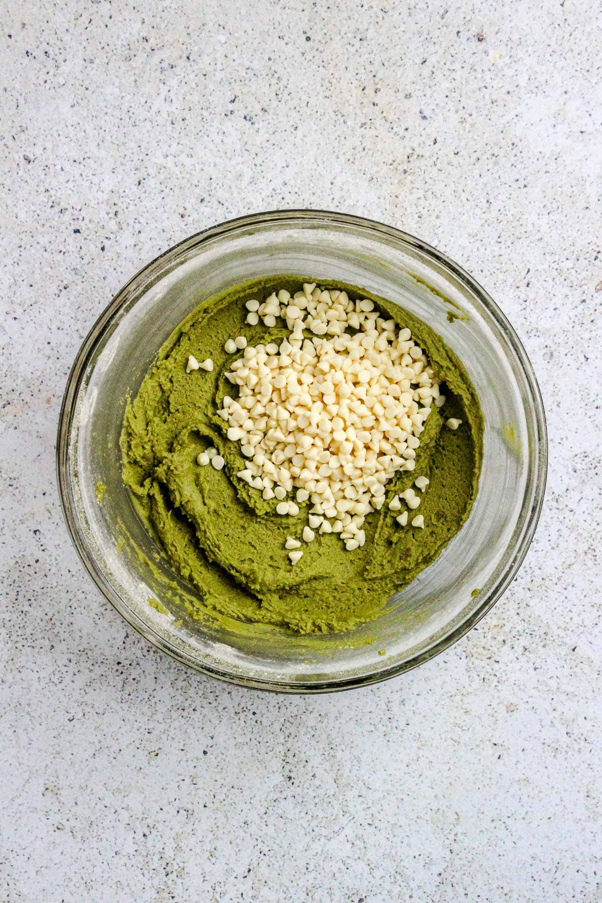 Matcha white chocolate chip cookie dough in a glass bowl.