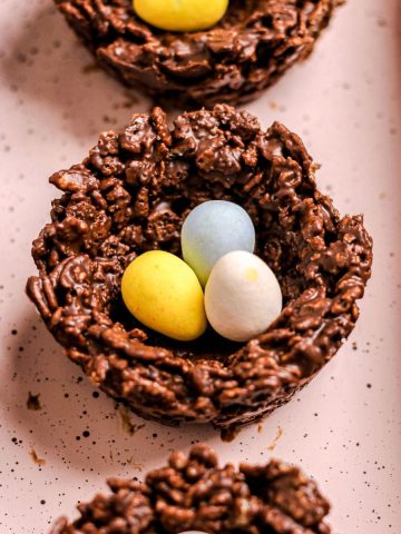 Birds nest cookies with mini chocolate eggs on a pink baking tray.