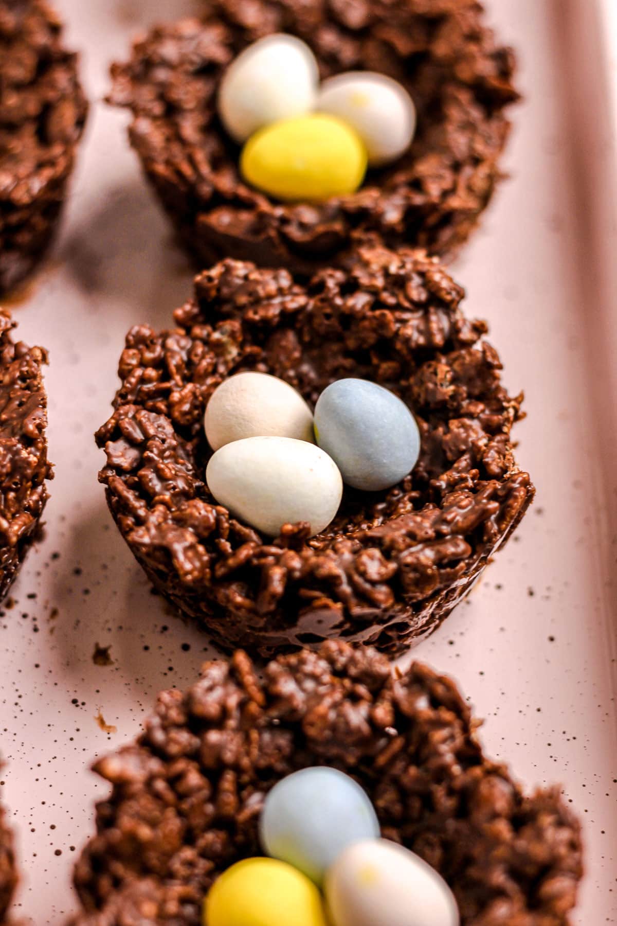 Birds nest cookies with mini chocolate eggs on a pink baking tray.