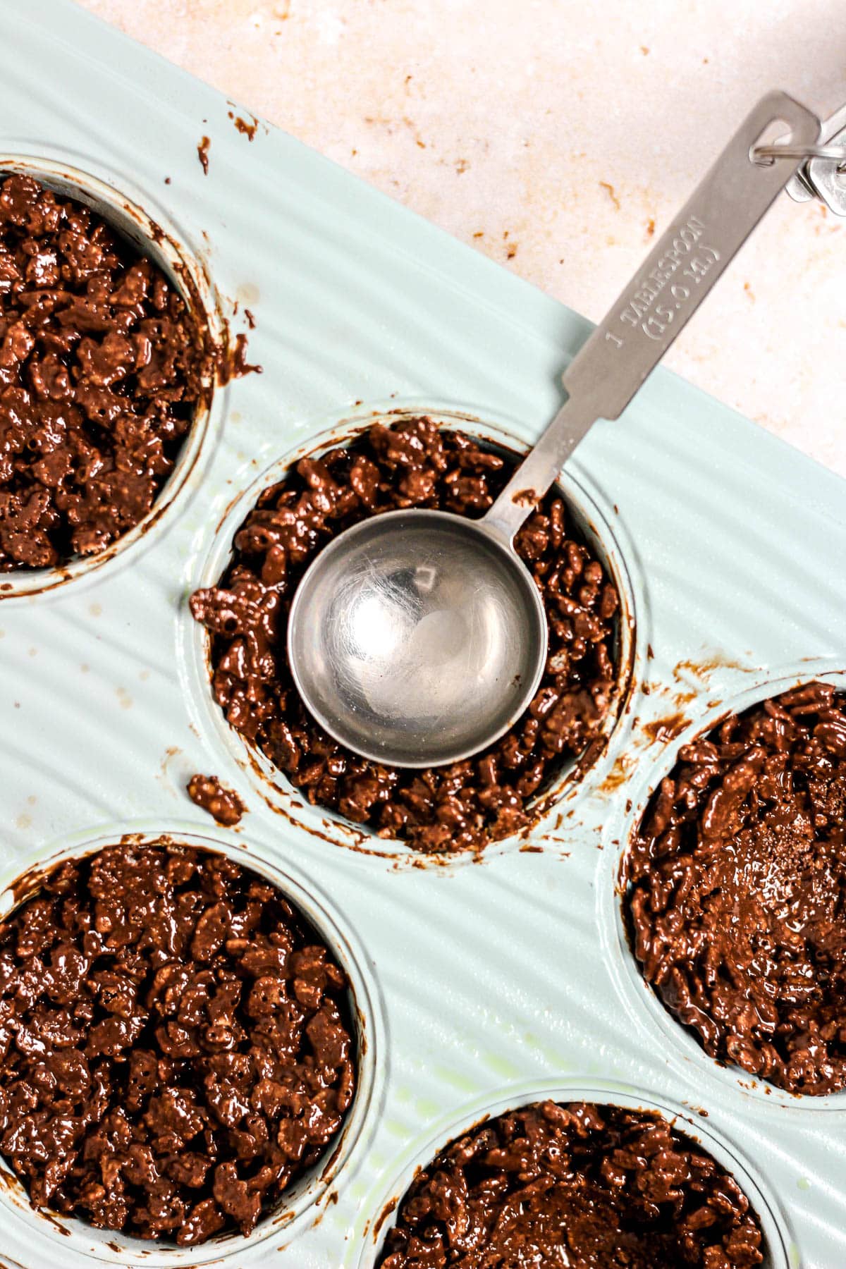 Chocolate peanut butter rice cereal mixture in a muffin tin for birds nest cookies.