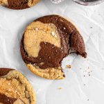Chocolate marble cookies with flaky salt on parchment paper.