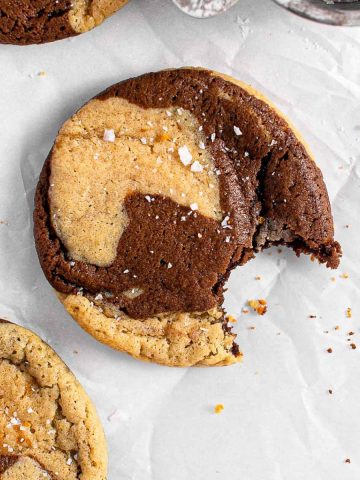 Chocolate marble cookies with flaky salt on parchment paper.