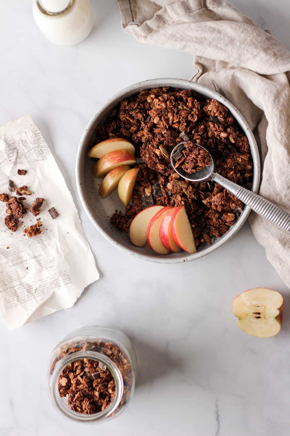 Chocolate Granola Recipe a bowl of chocolate chunk granola with a spoon and sliced apples for food photography