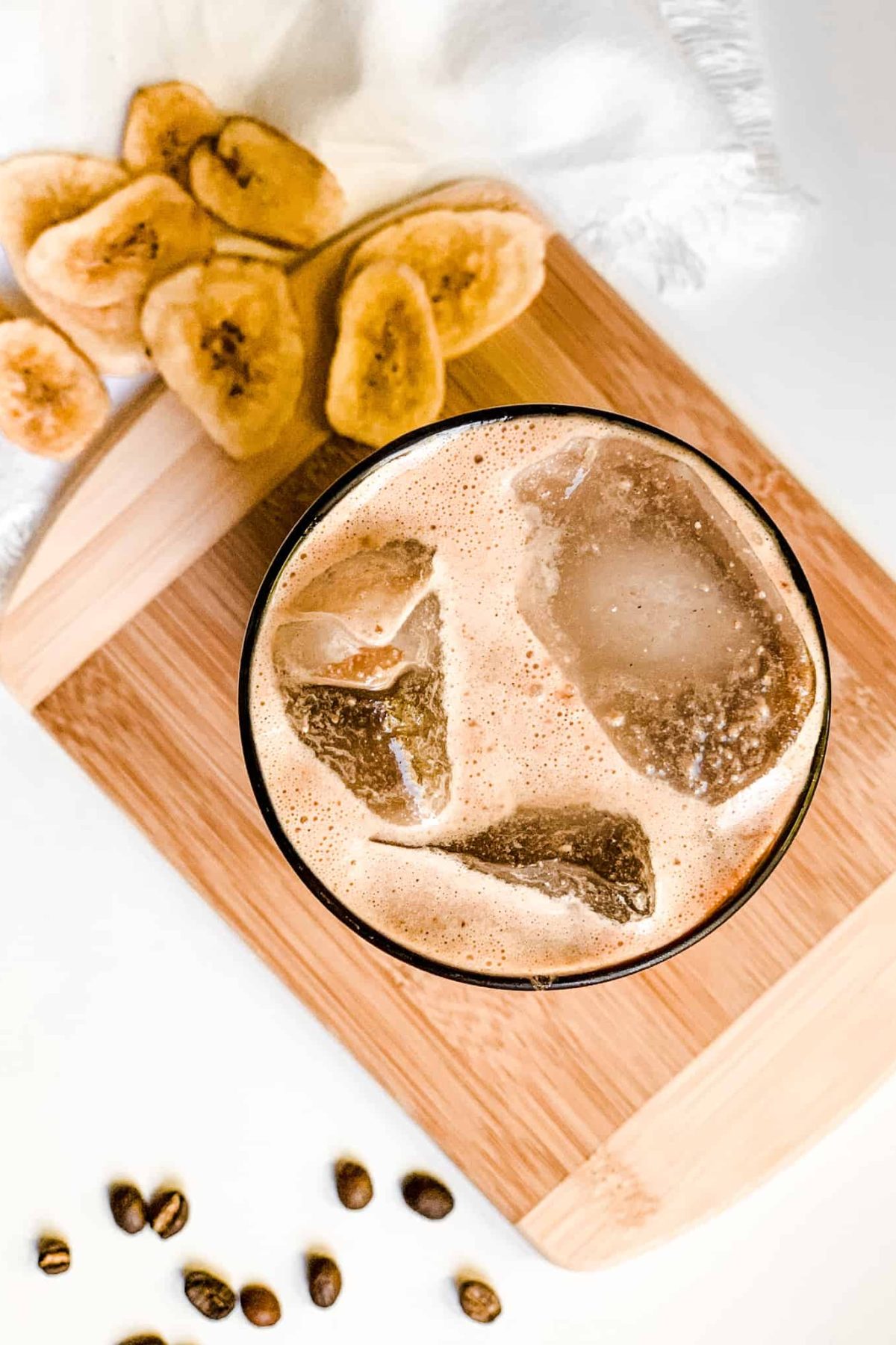 Creamy Banana Coffee Smoothie in a Tall Glass with Coffee Beans and Sliced Bananas for Food Photography