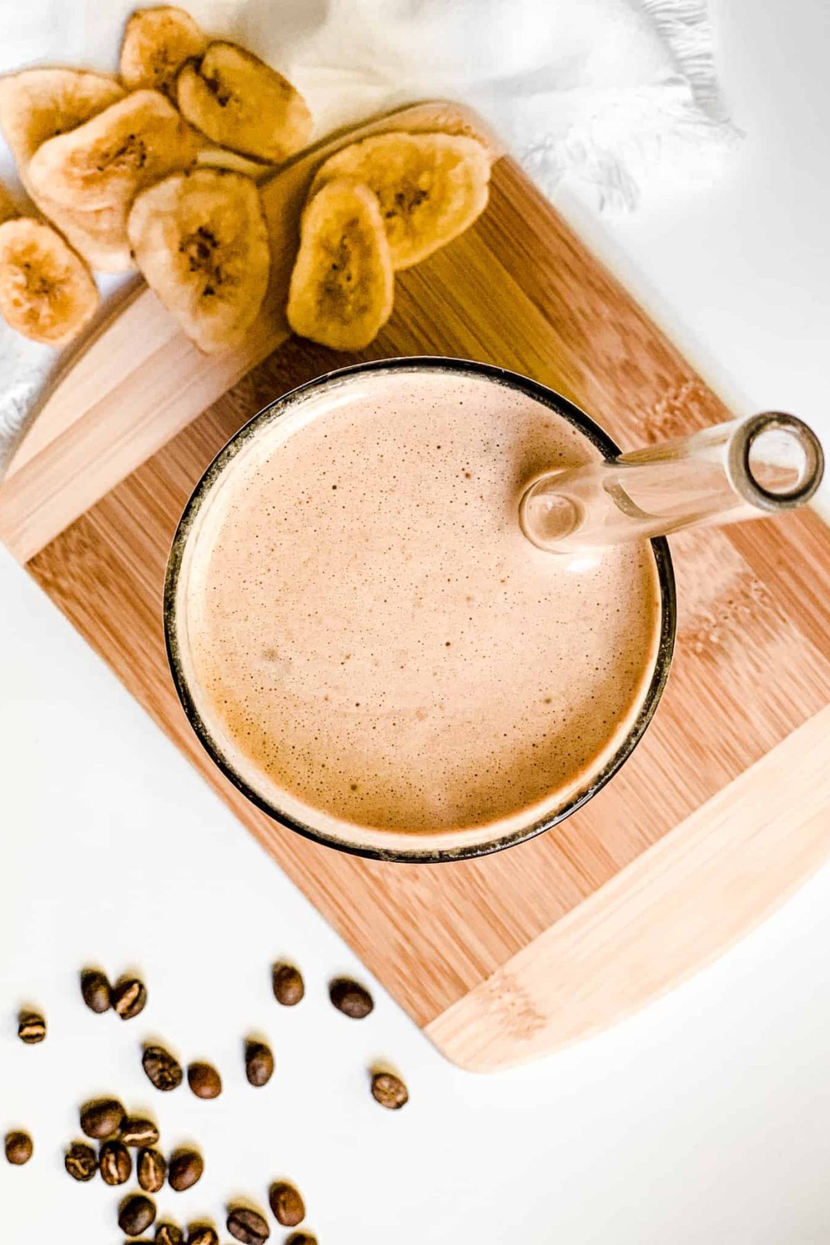 Creamy Banana Coffee Smoothie in a Tall Glass with Coffee Beans and Sliced Bananas for Food Photography