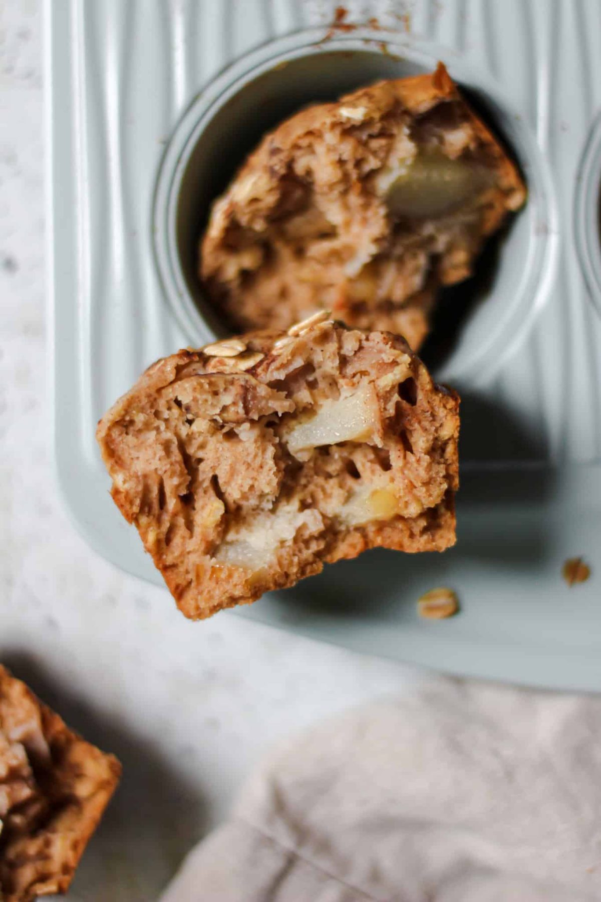 Healthy Pear Oat Muffins Flatlay food photo of the inside of a fruit muffin ripped in half sitting on a muffin pan