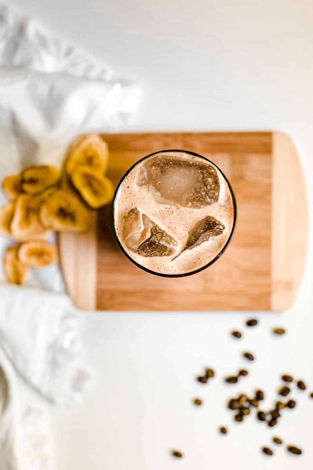 Creamy Banana Coffee Smoothie in a Tall Glass with Coffee Beans and Sliced Bananas for Food Photography