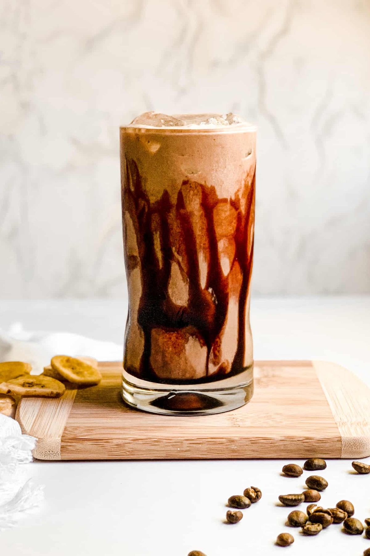 Creamy Banana Coffee Smoothie in a Tall Glass with Coffee Beans and Sliced Bananas for Food Photography