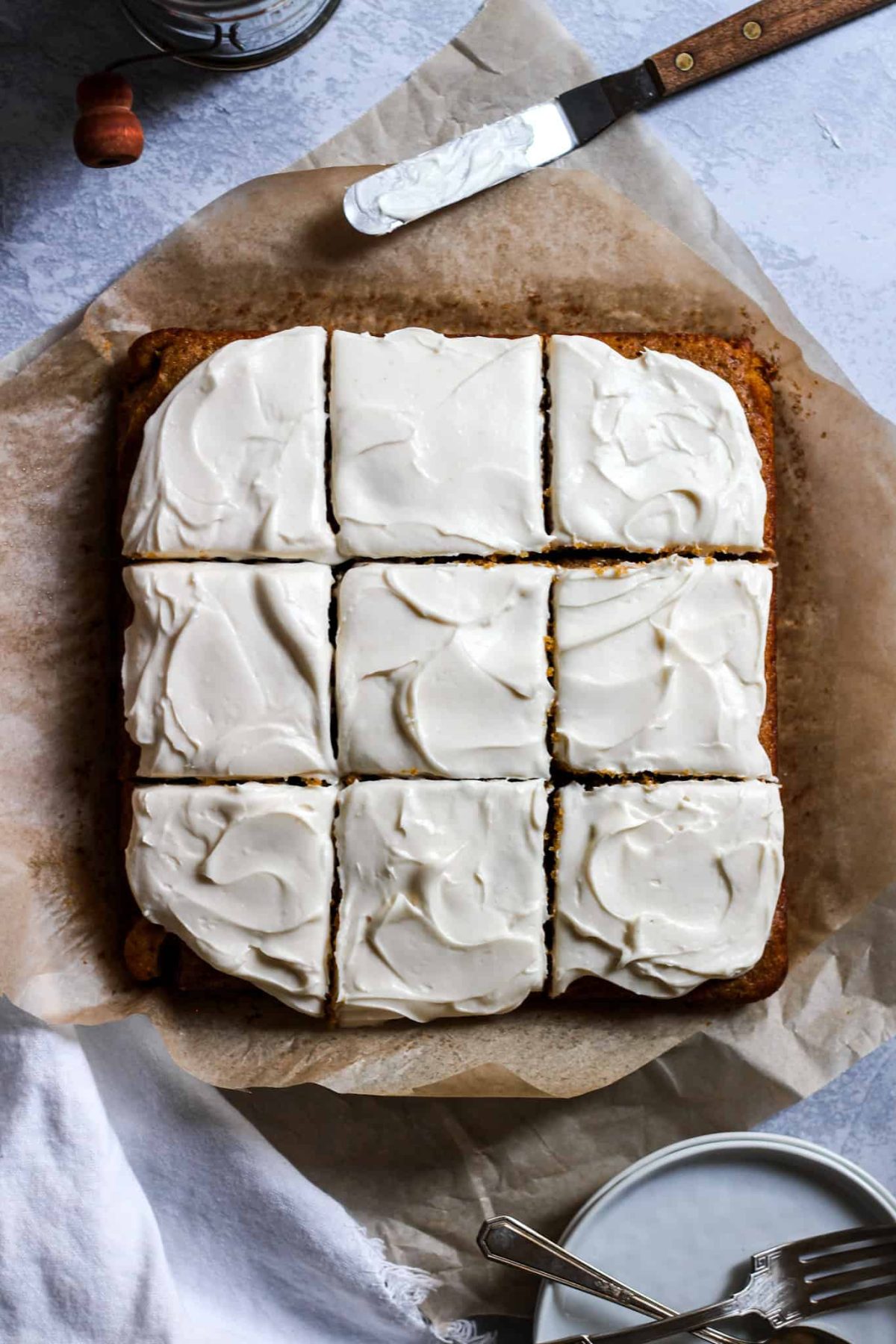 Pumpkin Cake with Cream Cheese Frosting Flatlay of fall cake with white icing cut into 9 squares