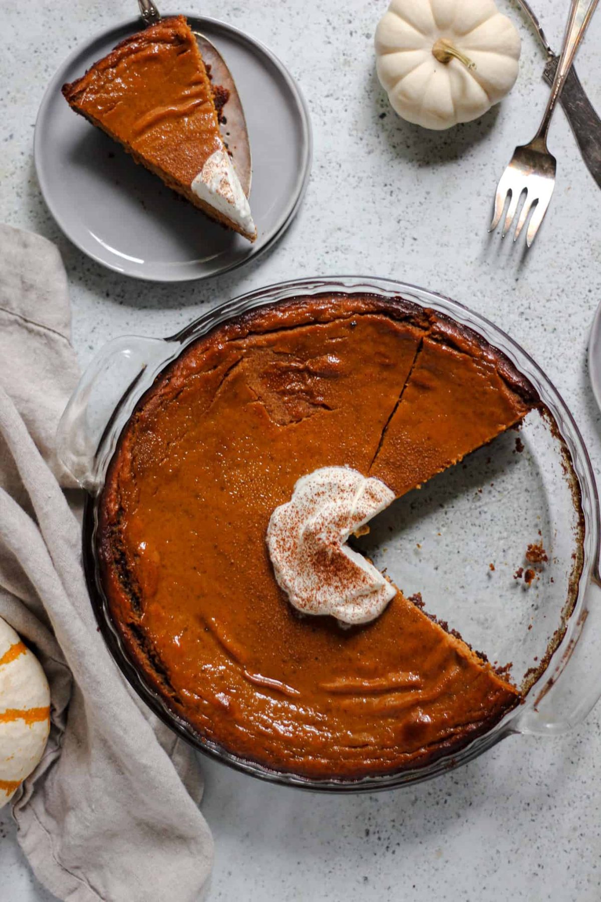easy pumpkin pie with gingersnap crust flatlay of pumpkin pie in a round glass dish with a slice of pie on a small grey plate